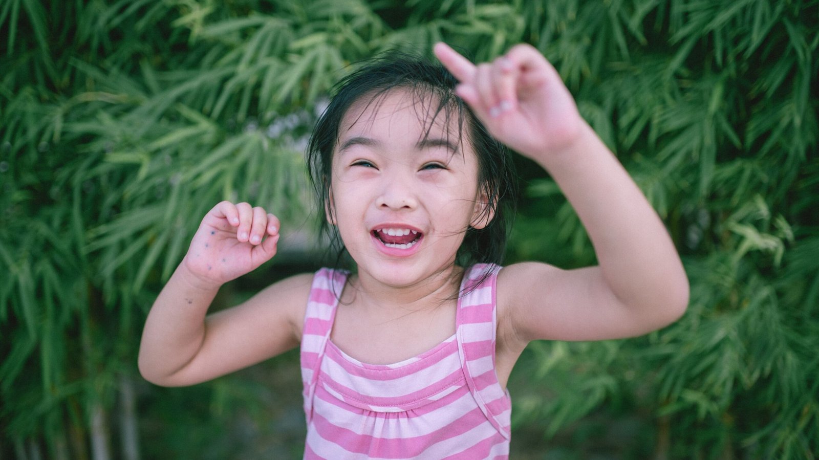A cheerful young girl in a striped top enjoying summer playtime outdoors.