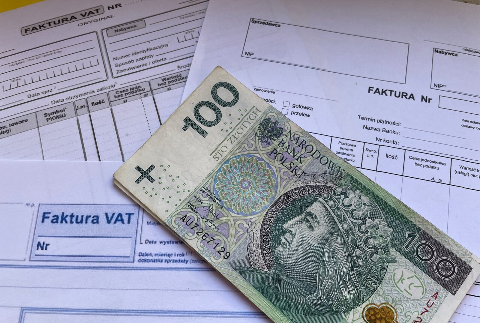 our-services-02 A 100 Polish Zloty note placed on top of business VAT invoices, symbolizing finance and economics.